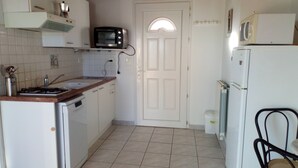 Une cuisine de taille réduite avec des meubles blancs, une cuisinière, un four à micro-ondes et un réfrigérateur.