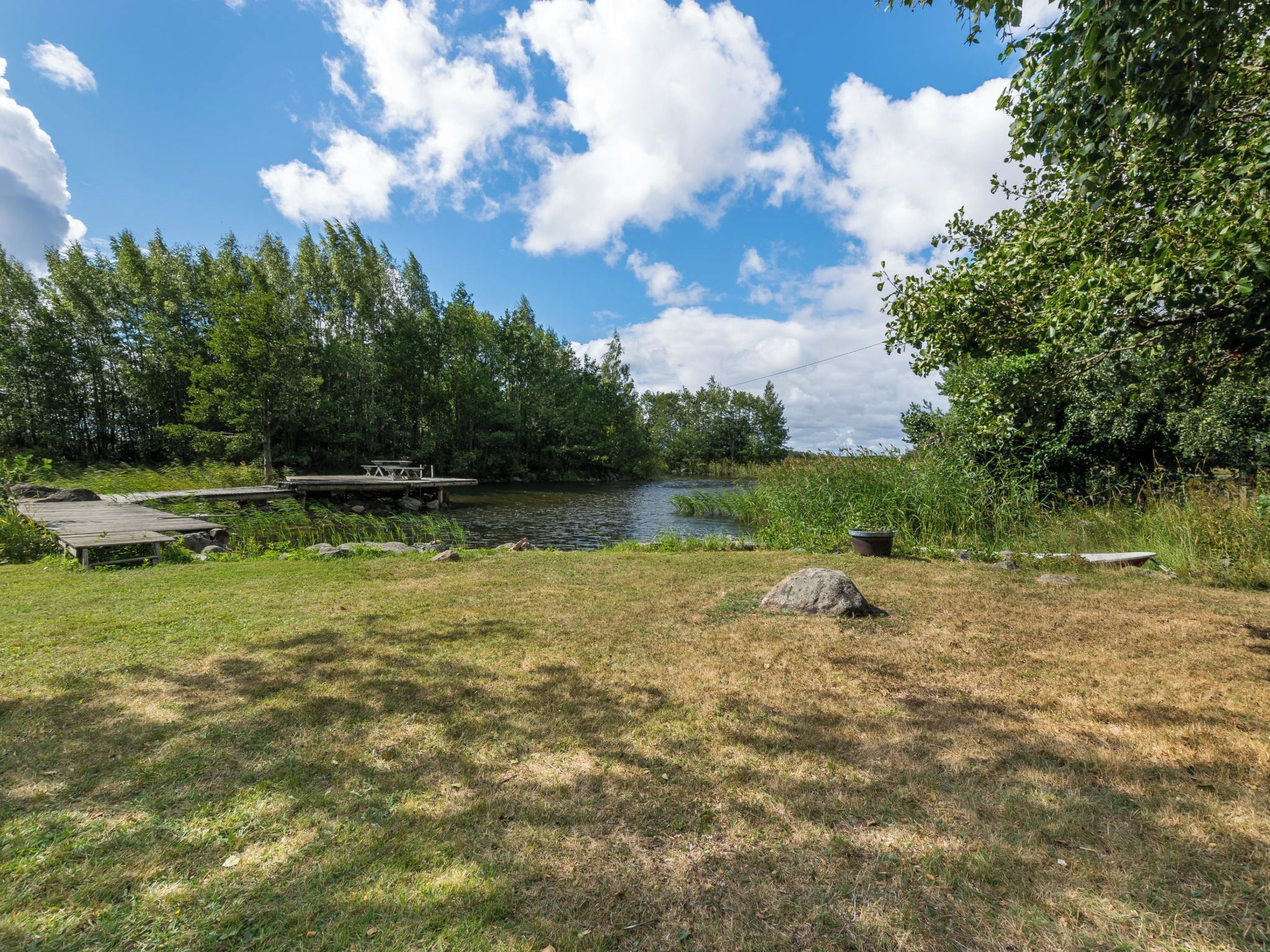 Un terrain de camping situé au bord de la rivière, équipé d’une table de pique-nique et d’une jetée en bois.