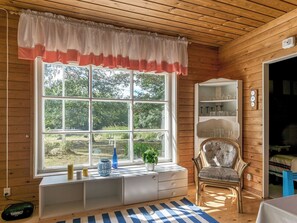 A room with a large window, a bookshelf, a chair, and a small table.