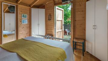 A wooden cabin bedroom with a bed, a television, and a large wardrobe.