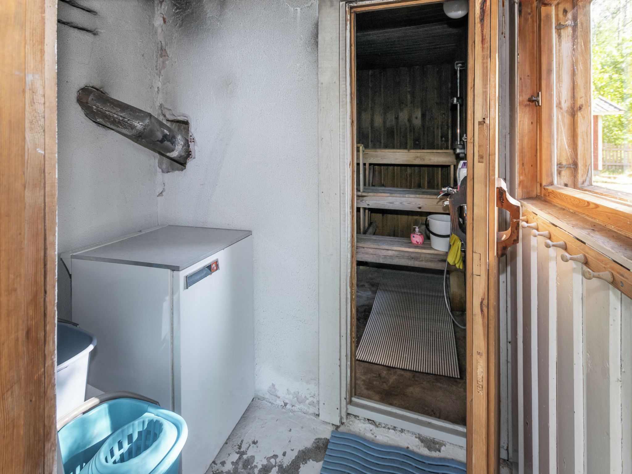 Cocina pequeña y funcional con refrigerador, lavamanos y estante de madera.