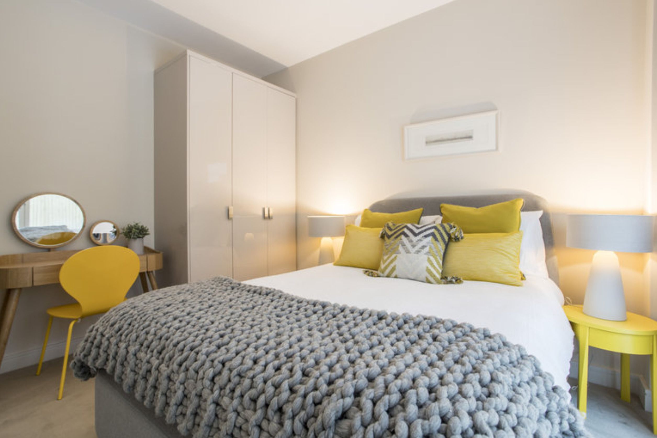 A bedroom with a bed, bedside tables, a desk, a chair, and a wardrobe.