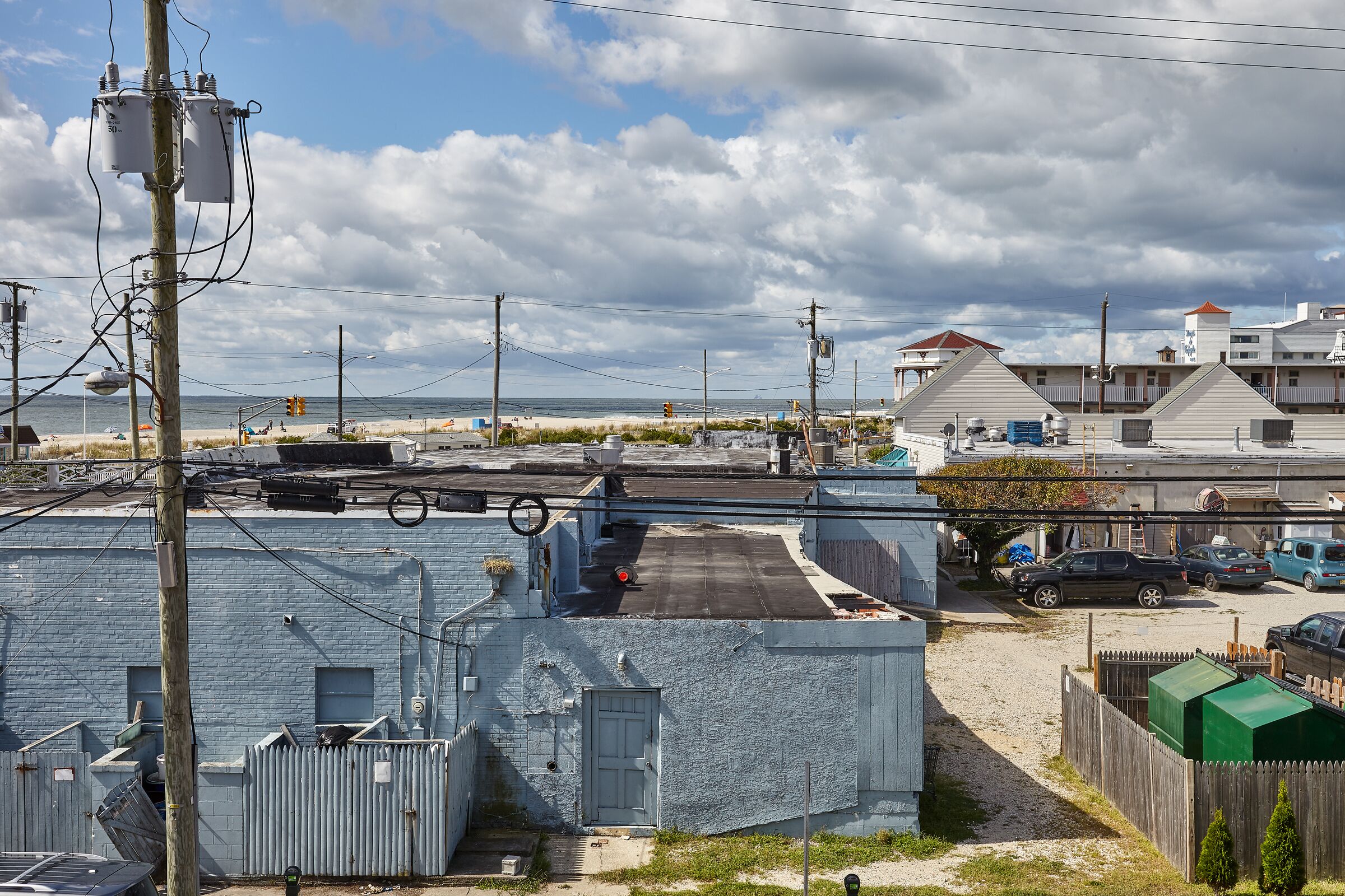 A coastal industrial area with buildings, a beach, and a parking lot.