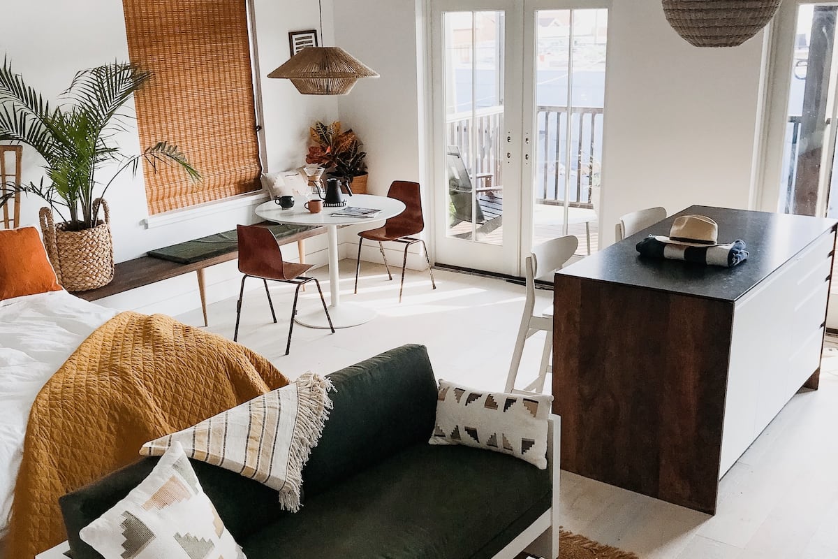 A modern living room with a green sofa, a coffee table, and a dining area with a small table and chairs.
