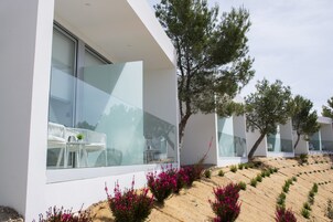 Un edificio moderno con amplios ventanales, terraza exterior y jardines ajardinados.