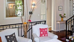 A living room with two white armchairs, a black metal railing, and a vase with branches and flowers. - Palermo Living Unique Rooms (Buenos Aires)