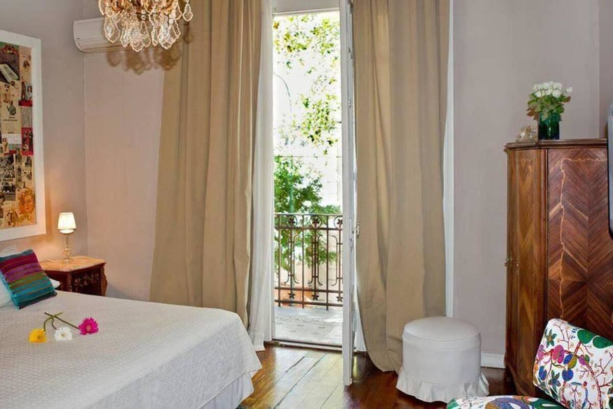 Un dormitorio con cama, mesita de noche, cómoda y ventana con cortinas.