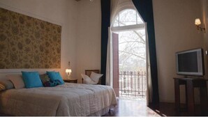 A bedroom with a bed, a television, a window with a view, and a patterned wall. - Palermo Living Unique Rooms (Buenos Aires)