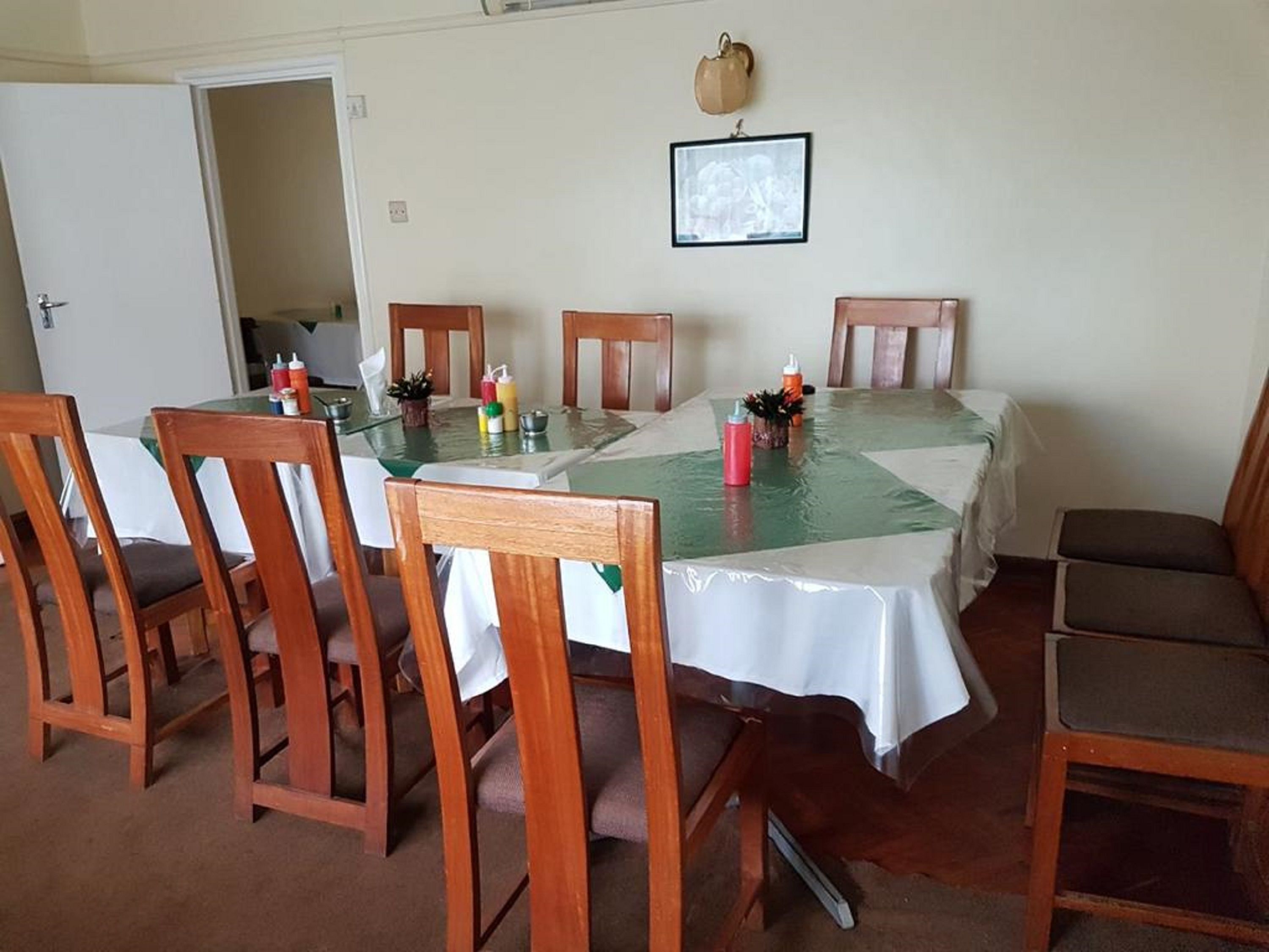 A dining area with a glass-top table, wooden chairs, and a white tablecloth.