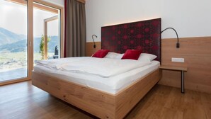 Une chambre à coucher moderne avec un cadre de lit en bois, une grande fenêtre donnant sur l’extérieur et une table de chevet avec une lampe.