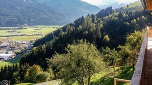 Un paysage de montagne avec vue sur une vallée et un bâtiment doté d’un toit en pente.