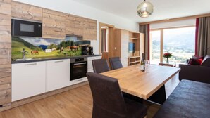 Une cuisine moderne avec des meubles en bois, un four à micro-ondes et une grande table à manger avec des chaises.