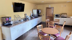 Una cocina con cafetera, microondas y televisión montada en la pared.