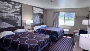 Habitación de hotel con dos camas, un ventanal con vistas, un escritorio con lámpara y decoración en la pared.