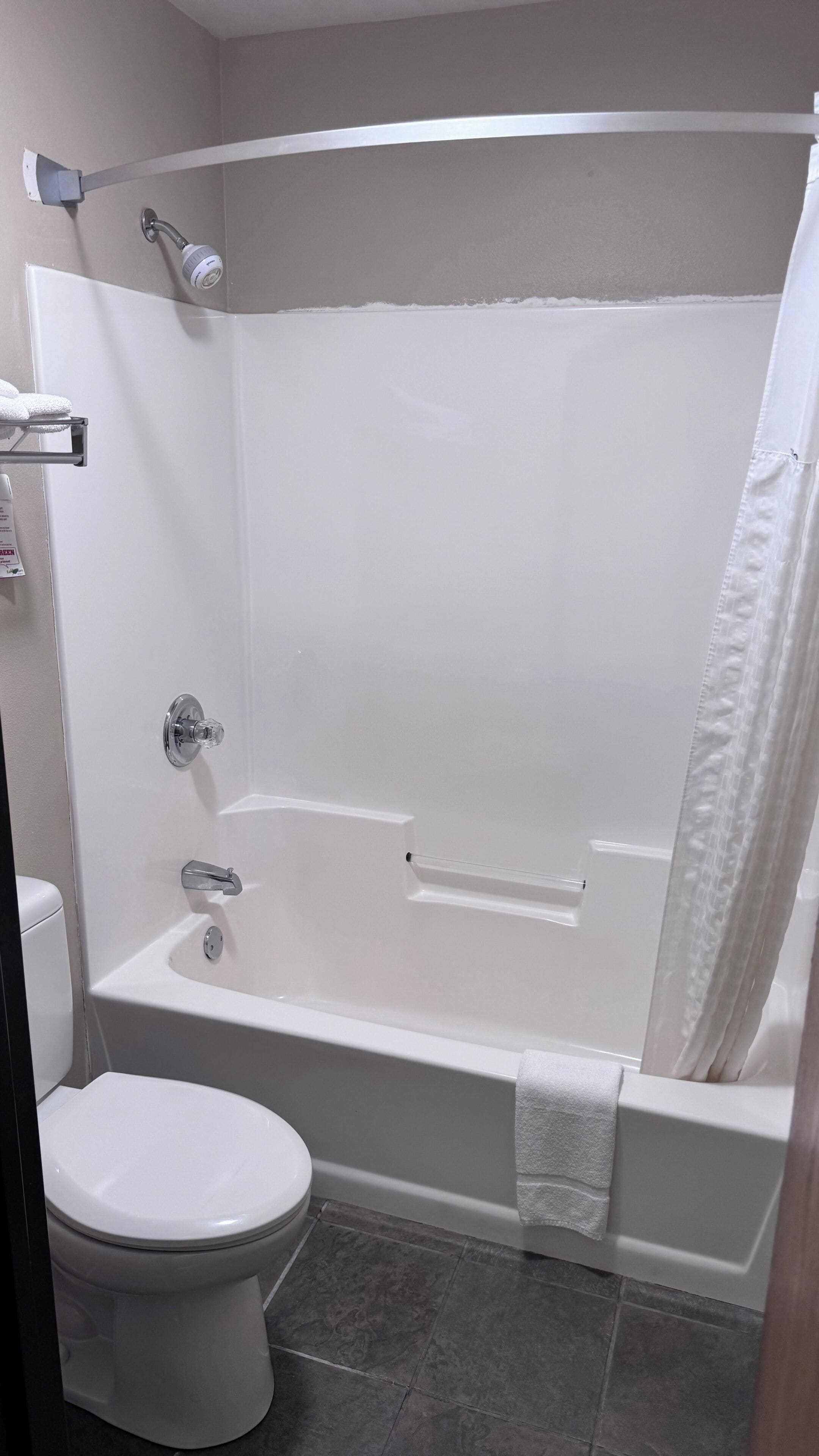 A bathroom with a bathtub, toilet, and shower curtain.