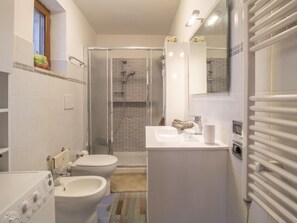 A modern bathroom with a shower, toilet, bidet, and sink.