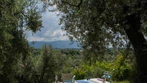 A secluded outdoor seating area with a pool and chairs, surrounded by trees and a mountainous backdrop. - Olive Grove Sabina by Interhome (Castelnuovo di Farfa)