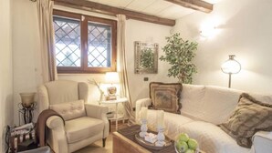 A cozy living room with a sofa, armchair, and a coffee table with decorative items. - Olive Grove Sabina by Interhome (Castelnuovo di Farfa)