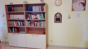Una habitación con una amplia estantería repleta de libros, un reloj de pared y un cuadro enmarcado.