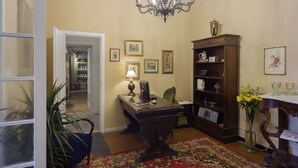 Ein Zimmer mit Schreibtisch, Stuhl, Bücherregal und einer Kristallleuchtre.