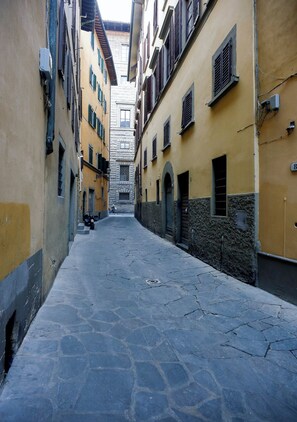 A narrow street with buildings on either side, featuring stone pavement and arched doorways. - Affittacamere nel Cuore di Firenze (Florence)