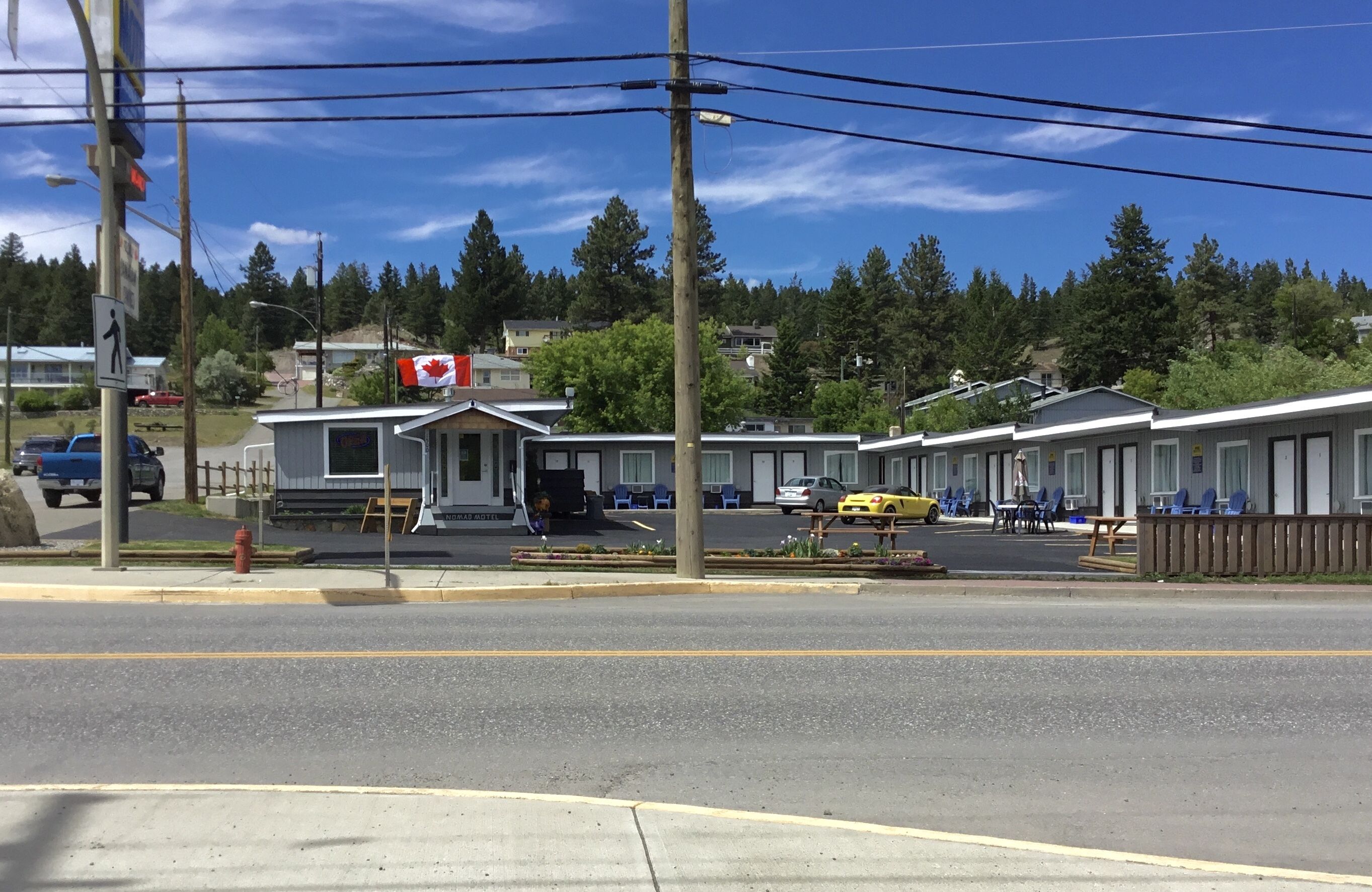Un motel con entrada central, habitaciones individuales a ambos lados y una bandera canadiense.