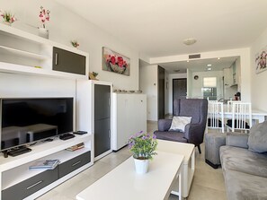 Un salon moderne doté d’un téléviseur à écran plat, d’un canapé, d’une table basse et d’un coin repas avec une chaise et une table.