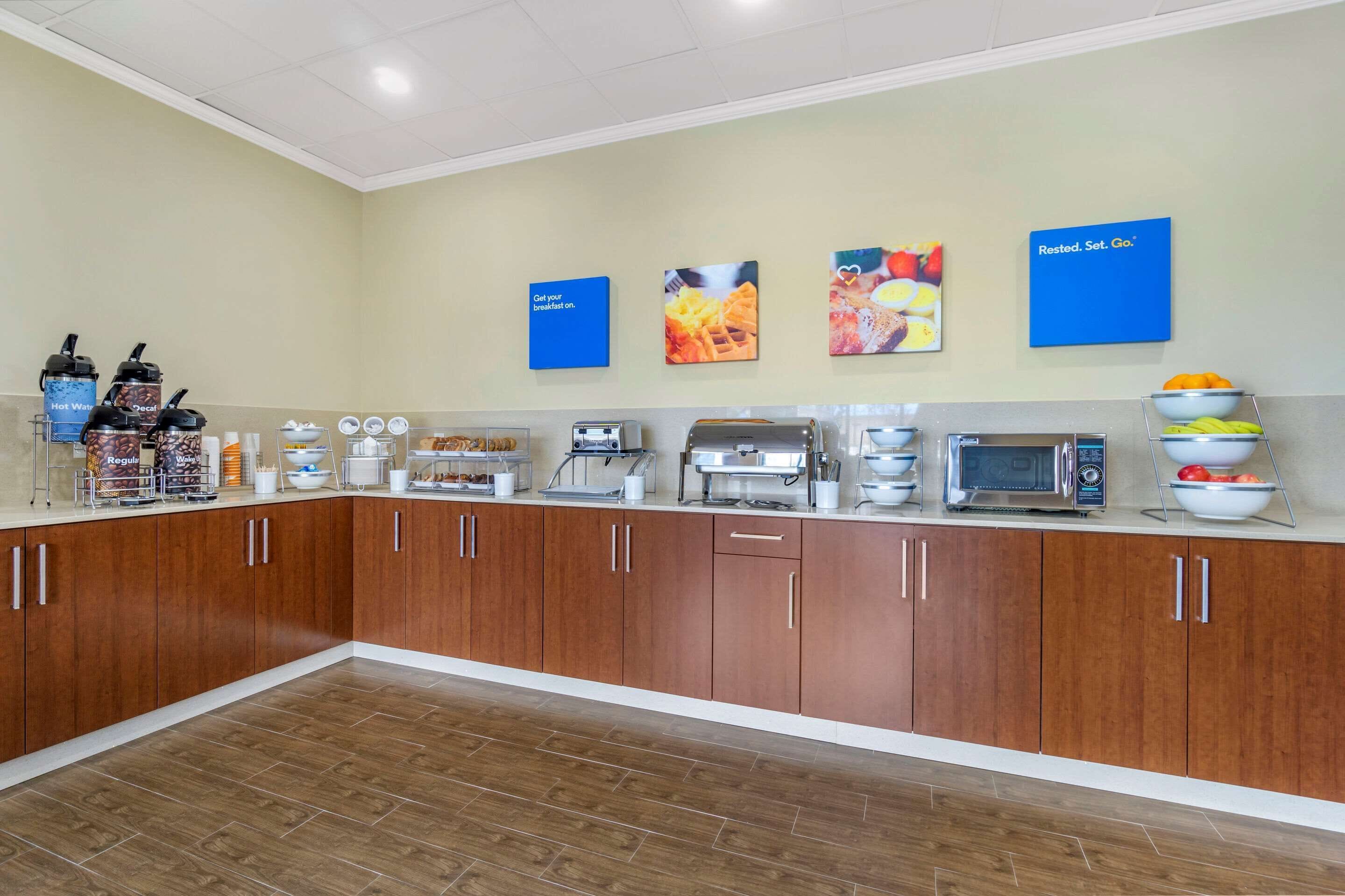 A breakfast bar with various food items, a microwave, and a coffee station.