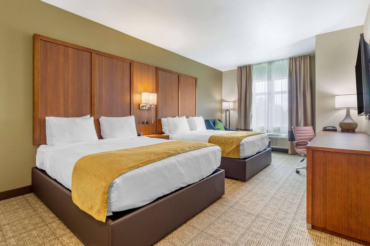Une chambre d’hôtel avec deux lits, un bureau et une chaise.