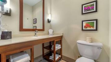 A bathroom with a wooden vanity, a sink, a toilet, and framed pictures on the wall.