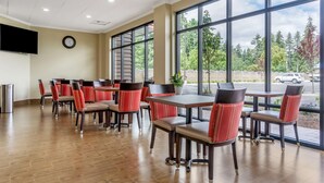 A spacious indoor area with wooden flooring, red and black chairs, and large windows offering a view of the outside. - Comfort Inn & Suites Lakewood by JBLM (Lakewood)