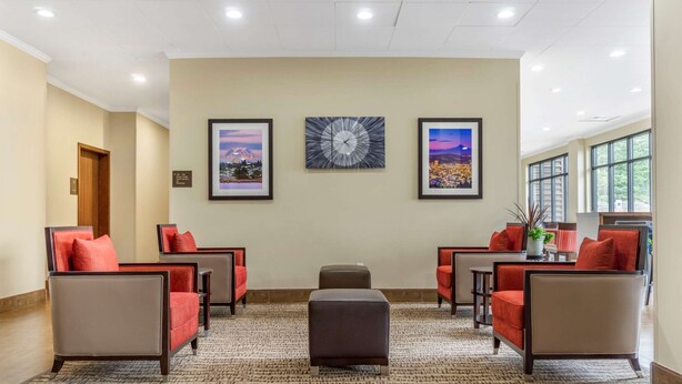 A lobby with four armchairs, a central ottoman, and framed artwork on the walls. - Comfort Inn & Suites Lakewood by JBLM (Lakewood)