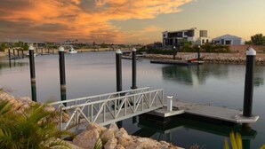 A marina with a dock, calm water, and modern buildings in the background. - 34 Madaffari Drive - Pet friendly Marina Property (Exmouth)