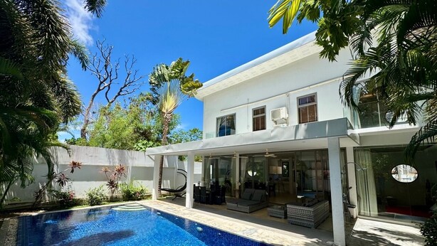 Une maison moderne dotée d’une piscine, d’un espace salon extérieur et d’un patio couvert.