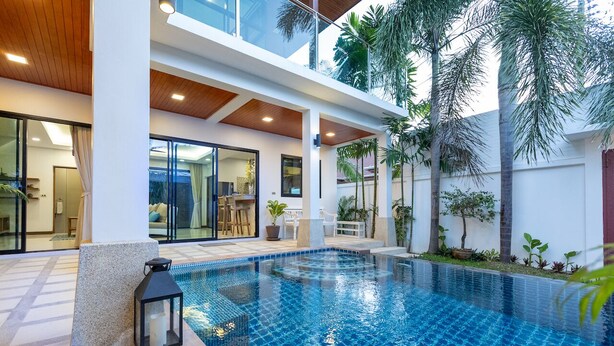 A modern indoor swimming pool with a tiled floor, surrounded by palm trees and a glass-enclosed patio area. - Rooftop Villa - Brand New 3BR Villa (Tambon Rawai)