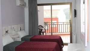 A hotel room with two beds, a balcony, and a view of a red building. - Hotel El Pino (Teror)