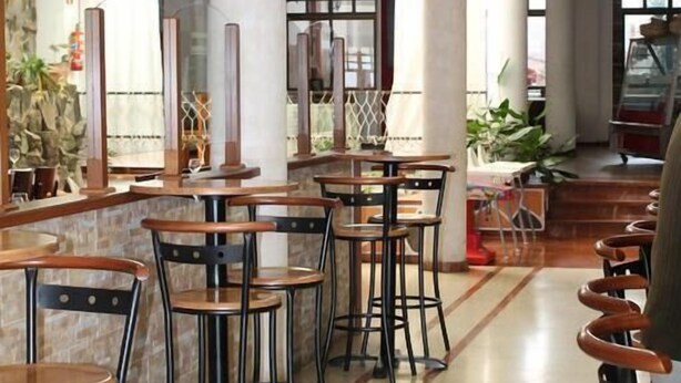 A spacious indoor area with multiple tables and chairs, large pillars, and a tiled floor. - Hotel El Pino (Teror)