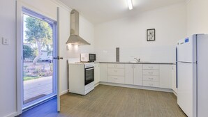 A modern kitchen with white cabinetry, a built-in oven, a microwave, and a refrigerator. - Getaway Villas Unit 38-11 - comfort on a budget (EXMOUTH)