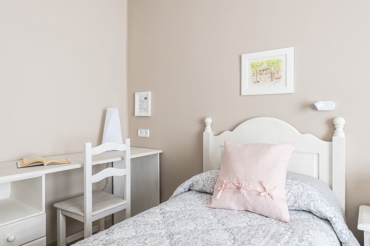 A bedroom with a bed, a desk, and a chair.