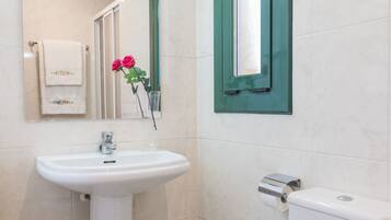 Un baño con un lavamanos blanco, un inodoro y un espejo.