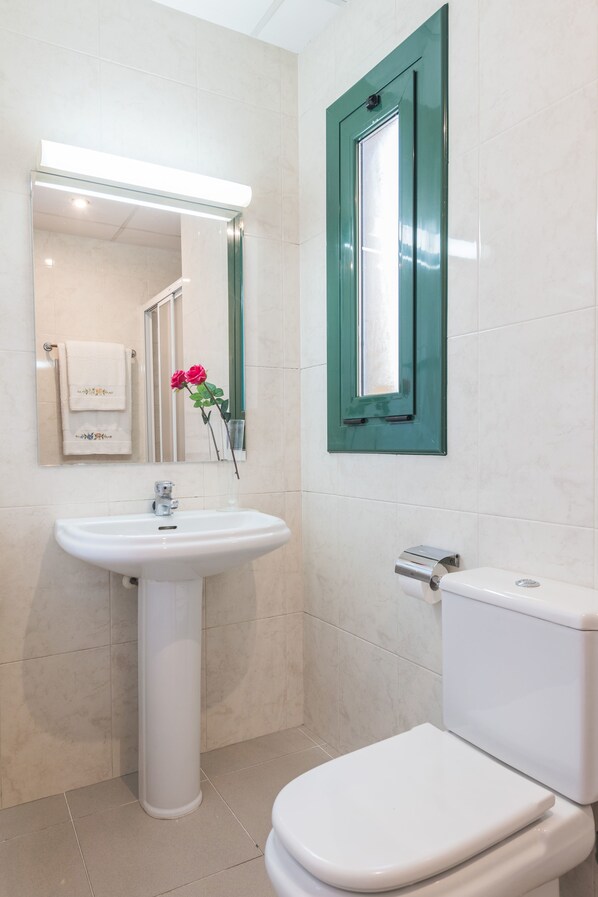 Un baño con un lavamanos blanco, un inodoro y un espejo.