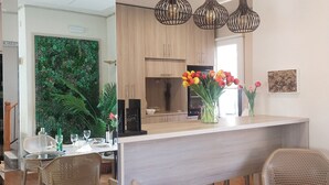 A modern kitchen with wooden cabinets, a central island with chairs, pendant lighting, and a view of the dining area.