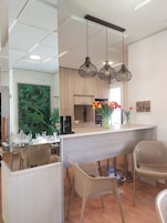 Una cocina moderna con armarios de madera, una isla central con sillas, iluminación colgante y vistas al área de comedor.