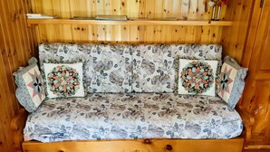 A wooden bench with floral upholstery and decorative pillows.