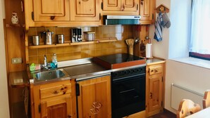 A kitchen with wooden cabinets, a stainless steel sink, and a built-in oven.