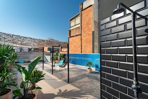 An outdoor patio area with a tiled floor, potted plants, a blue chair, and a blue wall with text.