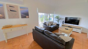 A living room with a sofa, a coffee table, a TV, and artwork on the wall.