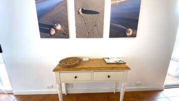 A white desk with two drawers and a woven basket, a small stack of cards, and a decorative tray on a wooden surface.