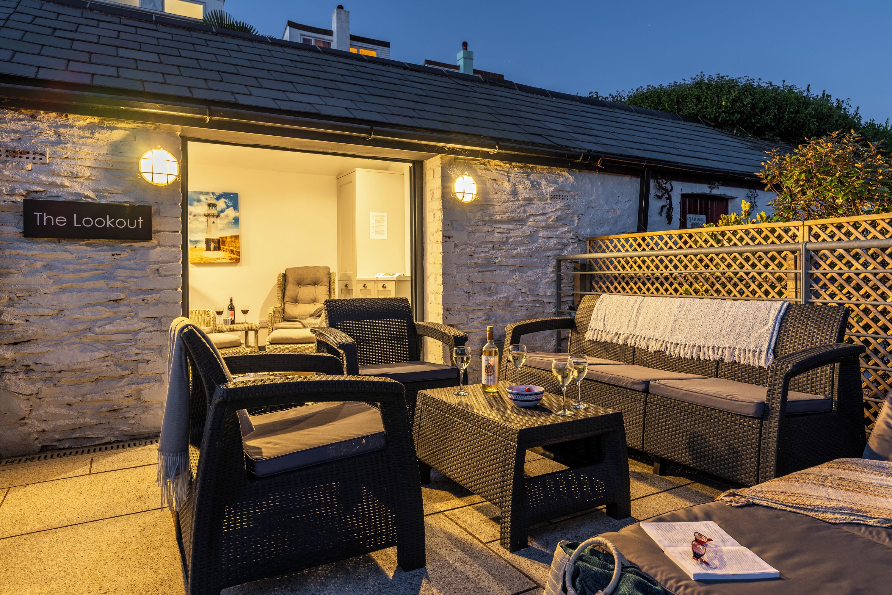 An outdoor seating area with wicker furniture, a table with wine glasses, and a sign reading "The Lookout".