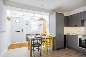Una cocina moderna con armarios grises, una mesa de comedor con sillas amarillas y una preparación para el desayuno.